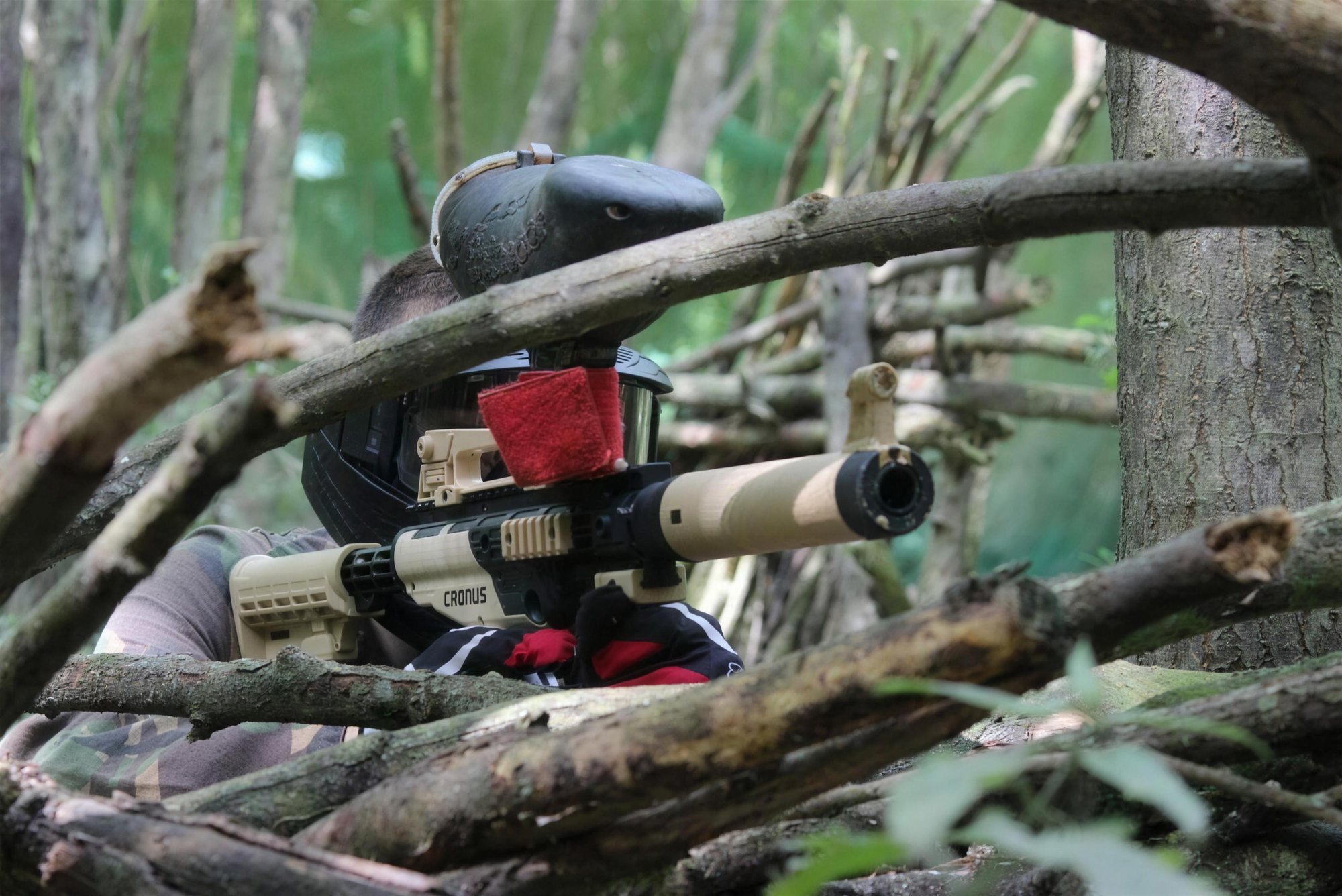 A paintball marker resting on branches at the edge of a field