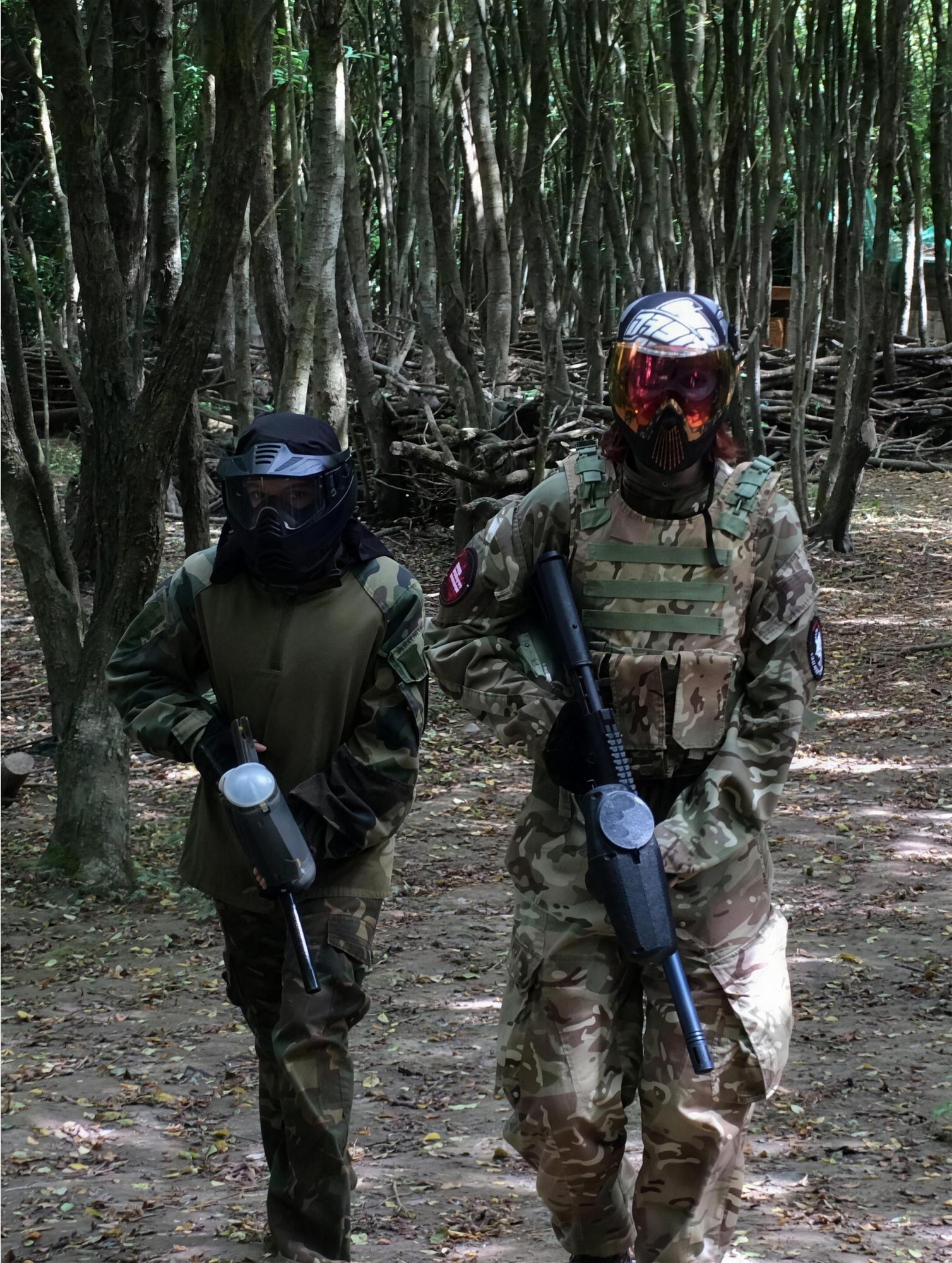 Two players advancing through the woodland with paintball markers